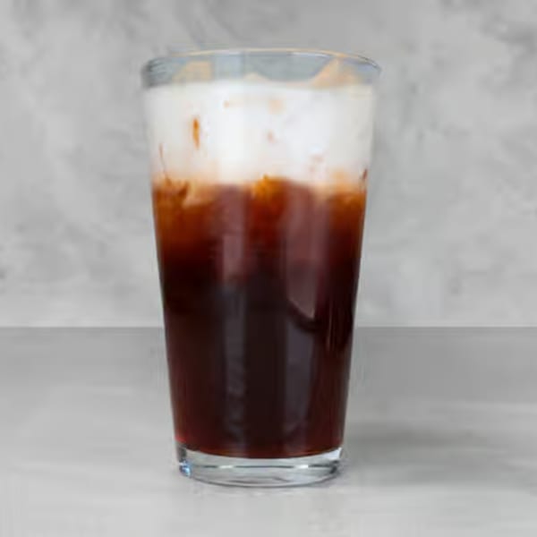 A tall glass of iced Thai tea with a dark amber base and a creamy white top layer.