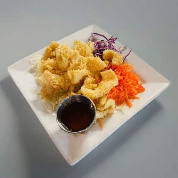 Crispy fried tofu with shredded cabbage, carrots, and purple cabbage, served with a dipping sauce.