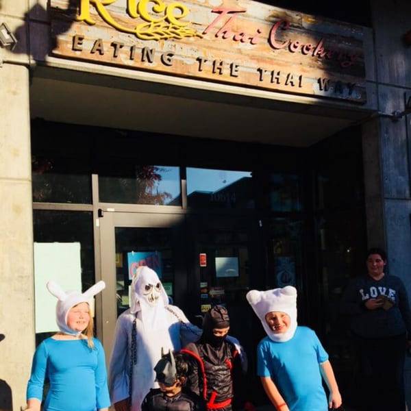 Children in Halloween costumes stand outside Rice Thai Cookery, a Thai restaurant.