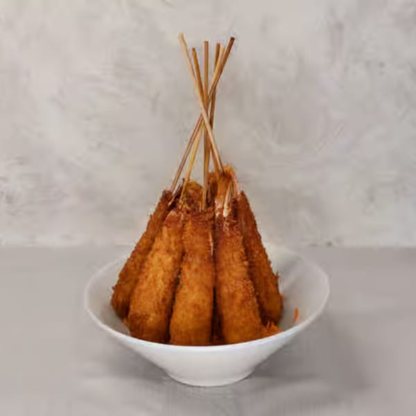 Golden-brown fried shrimp skewers, arranged upright in a white bowl, against a light background.