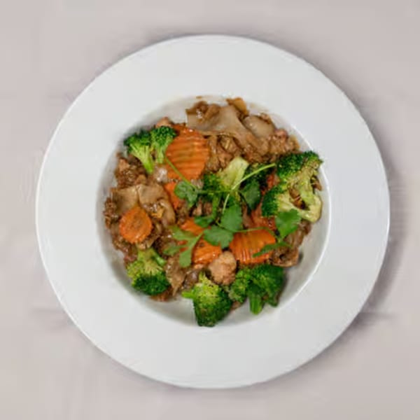Thai stir-fry with broccoli, carrots, and meat, garnished with cilantro on a white plate.