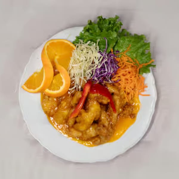 Orange chicken with red bell pepper, shredded cabbage, carrots, and lettuce on a white plate.